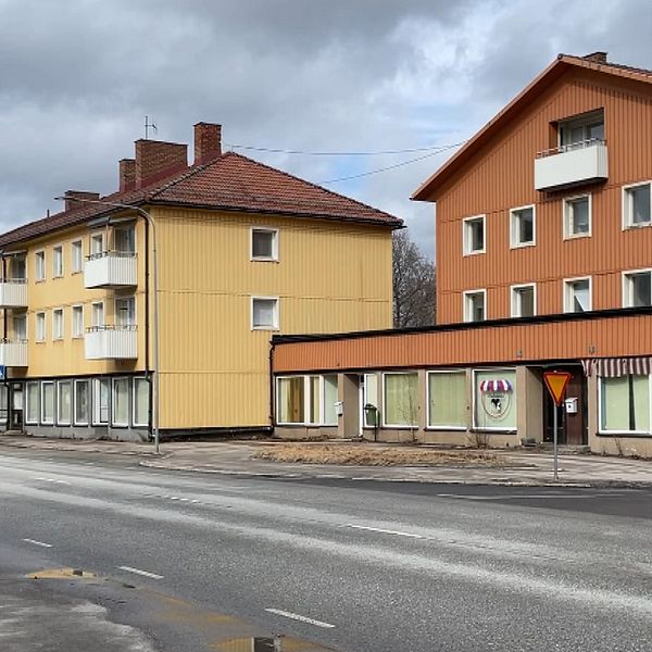 Vänsterbild: glasskross på marken. Höger: Bilden  visar en stadsmiljö från Ställdalen med byggnader och en gata. Detaljerna är som följer:  Byggnader: Det finns flervåningshus i olika färger; ett gult hus närmast och ett orange bakom det. Gata: På gatan syns vägmarkeringar och det finns inga fordon eller personer i sikte. Väder: Himmelens färg tyder på att det är molnigt eller disigt väder.