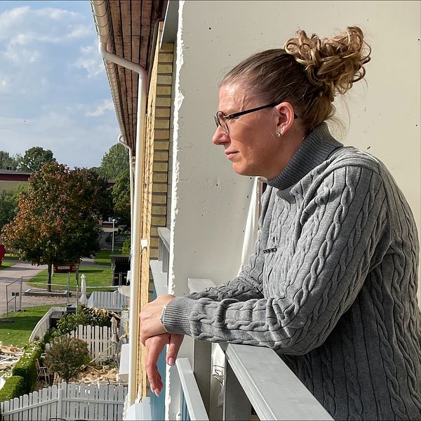 Britt-Louise Malmlöv står i sin balkong och tittar ner. Ekholmen, Linköping.