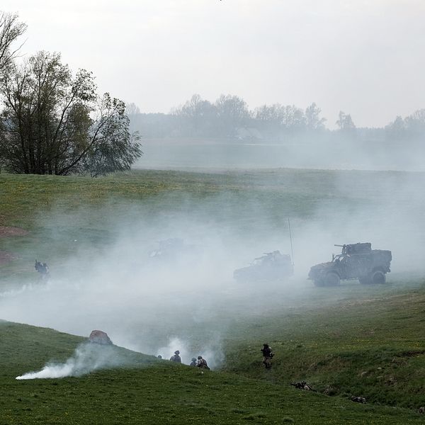 Soldater övar i rökig terräng, en soldat i förgrunden med vapen