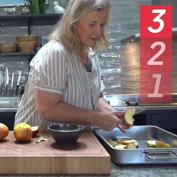 Annika Bergman står i sitt kök och skär äpplen i klyftor över en skärbräda.