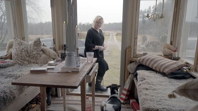 Rektor Anna står i entrén till en byggnad.