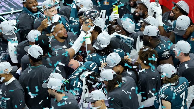 Spelare i Philadelphia Eagles firar med Super Bowl-trofén efter en seger, omgivna av konfetti.
