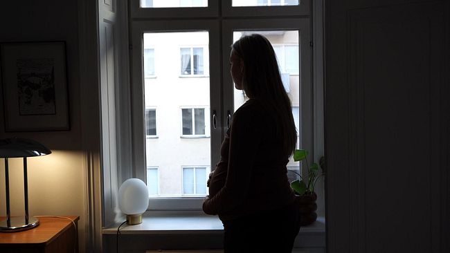 Silhuett av gravid kvinna i fönster