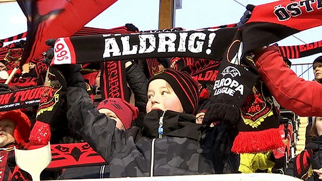 ÖFK-supportrar står och viftar med flaggor och halsdukar ovanför huvudet.