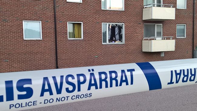 Krossat fönster i lägenhetshus. Polisens avspärrningsband.