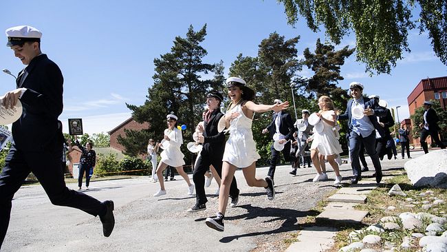 Studenter på Nacka gymnasium springer ut ur skolan på studenten.