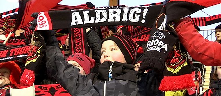 ÖFK-supportrar står och viftar med flaggor och halsdukar ovanför huvudet.