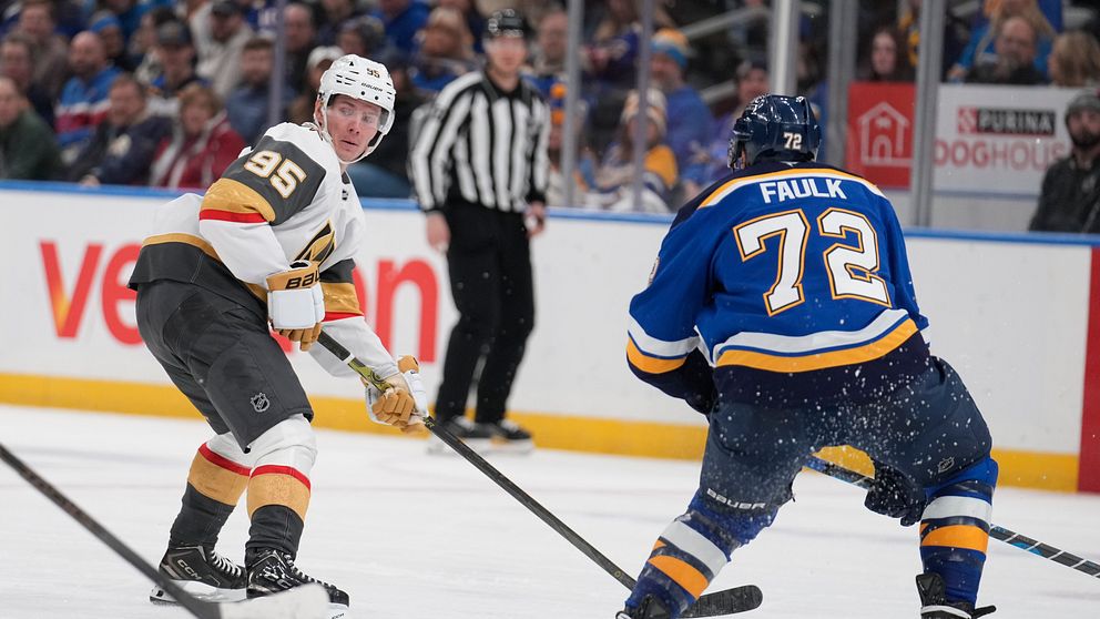 Två hockeyspelare i aktion under en match, en i svart och guldtröja med nummer 95 och en annan i blå tröja med nummer 72. Refereen i svart och vitt står i bakgrunden. Snön sprutar upp från isen när de två spelar på en rinken.