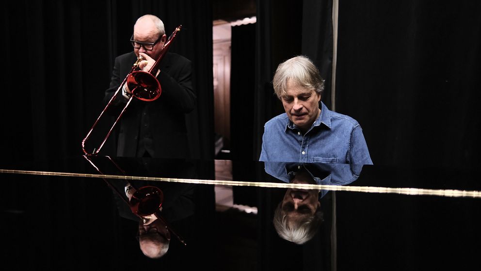 Musiker spelar trombon bredvid en flygel.