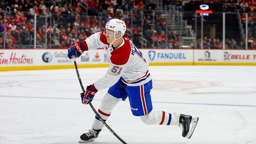 Hockeyspelare från Montreal Canadiens skjuter pucken mot mål under en match. Spelaren är iklädd lagets vit-röda tröja med nummer 51. I bakgrunden syns publik och reklamskyltar.