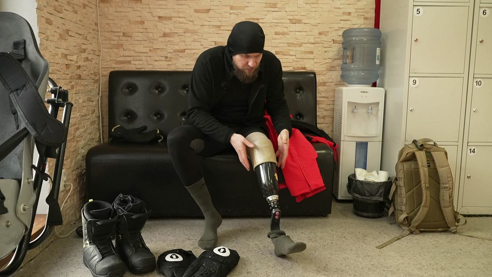 Andrij sätter på sin benprotes i ett omklädningsrum inför snowboardåkning.