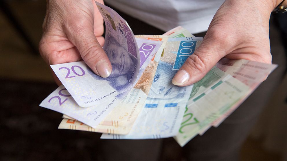 Kvinna visar sedlar och håller dem som en solfjäder i handen.
