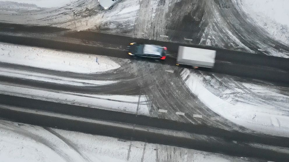 En bil med ett släp på en snöig väg. Bilden är tagen från ovan med en drönare.