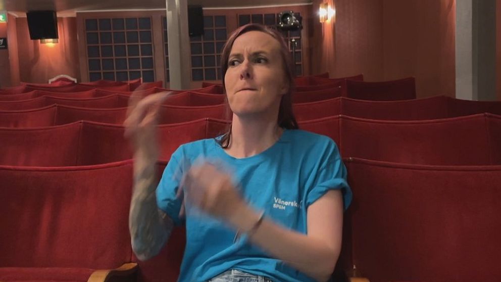 Sofia Erenmalm applåderar i en tom salong med röda säten