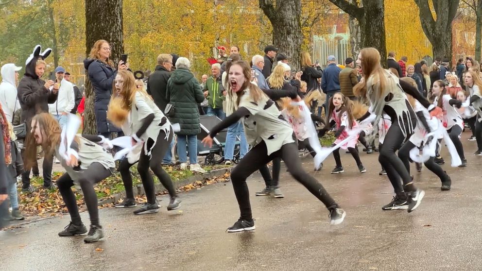 Ett gång dansare utklädda till Zombies skriker på gatan framför en publik