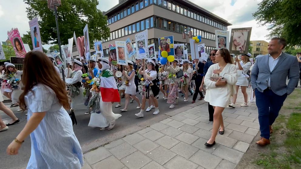 Studenter i vita mössor firar på ett torg med publik runtomkring