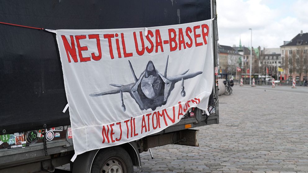Banderoll med texten ”Nej til USA-baser, nej til atomvåben” och bild på ett militärflygplan.