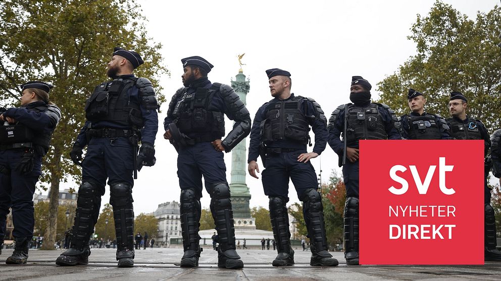 Poliser står vakt vid demonstration i Paris, SVT Nyheter Direkt-skylt i förgrunden