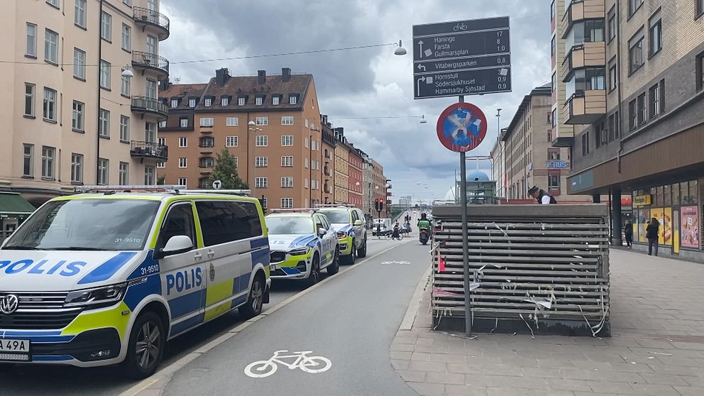 Polisbilar parkerade längs gata i stadsmiljö efter misstänkt guldrån i Stockholm.