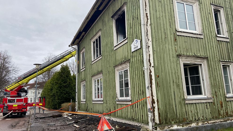 brandbil framför ett grönt trähus som brunnit