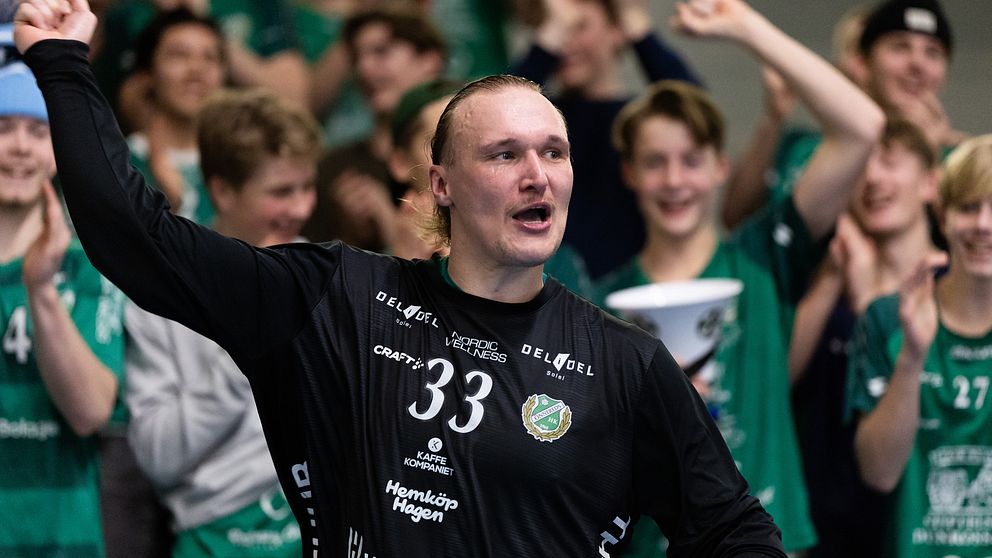 En handbollsspelare med nummer 33 på sin tröja jublar framför en entusiastisk publik klädd i grönt och vitt.