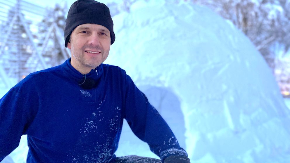 en man i tröja och mössa syns framför en igloo i snö