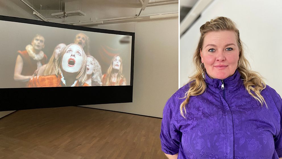 Em kvinna som står framför en stor skärm i en konsthall