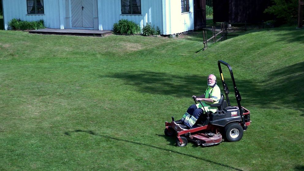 Pelle Schunnesson, huvudansvarig för Ransäterstämman, sitter i en åkgräsklippare på en gräsmatta utanför ett vitt hus.