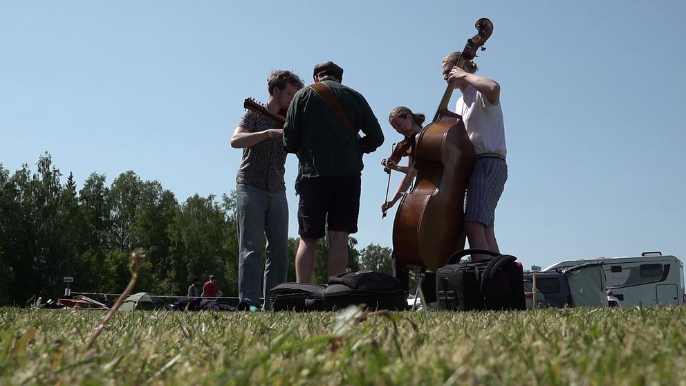 En grupp människor spelar stråkinstrument utomhus i samband med Ransäterstämman.