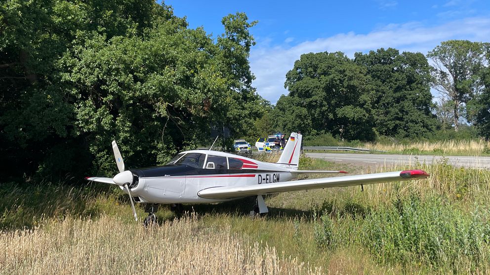 Flygplanet som tvingades nödlanda på gamla E22:an söder om Kalmar under tisdagseftermiddagen står vid sidan av vägen. Polisbilar i bakgrunden. Foto: Ludwig Fleetwood/SVT