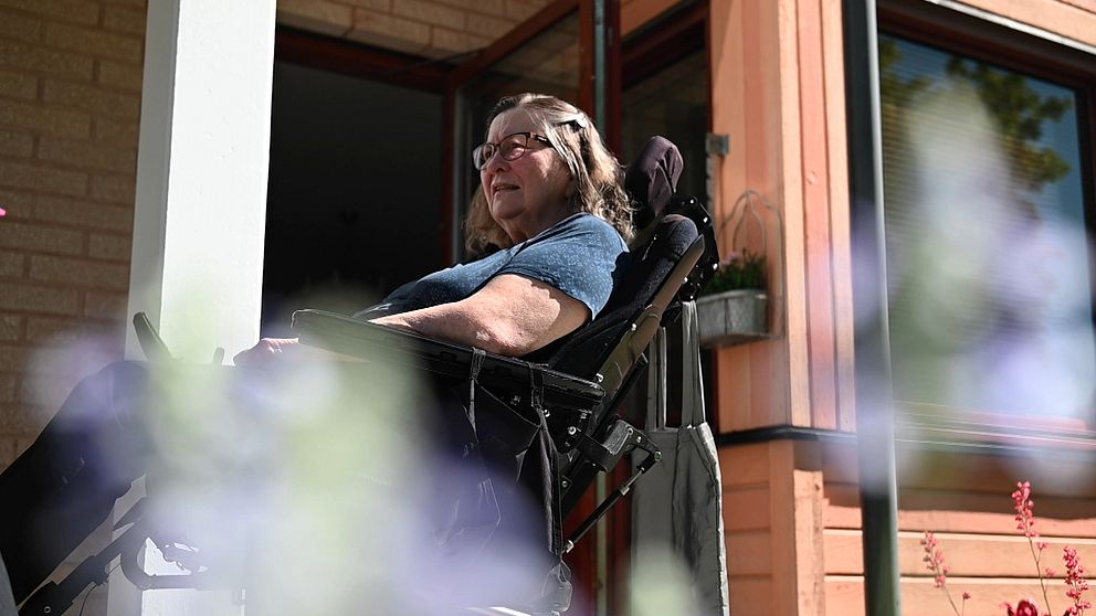 Hillevi Andersson i rullstol på en balkong vid sitt hem