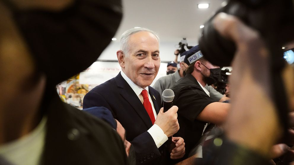 Benjamin Netanyahu talar med mikrofon bland fotografer