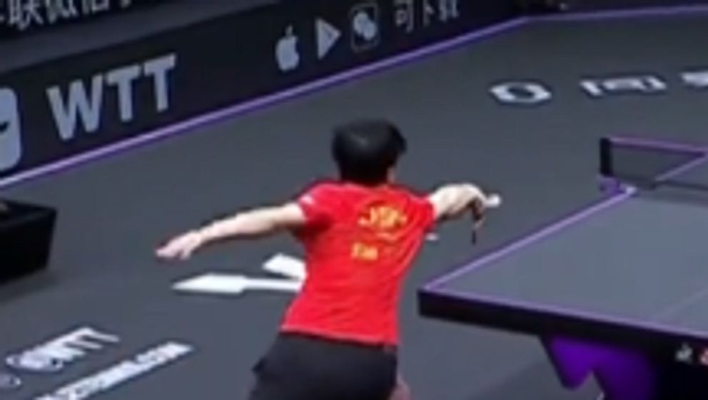 Bordtennisspelare i röd tröja tar ett välkänt slag under match.