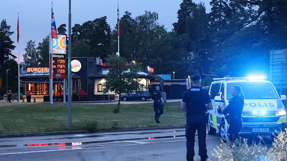 Polisen står framför en snabbmatsrestaurang. Det är kväll. Polisbilden