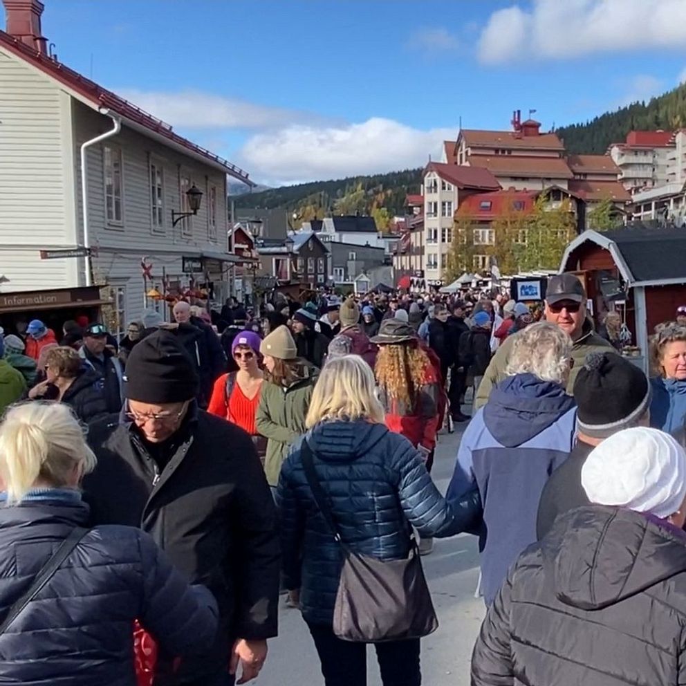 En livlig marknad till vänster med många människor som promenerar på en gata.