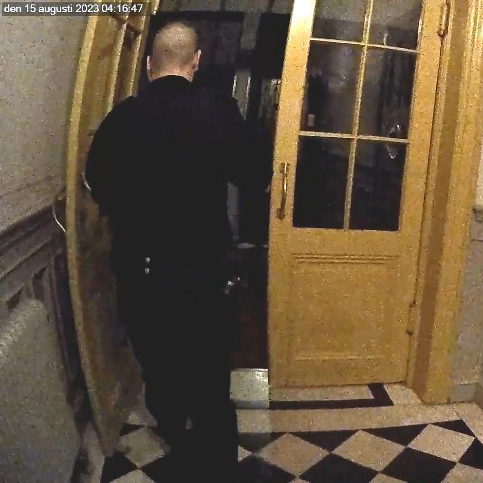 En polis är påväg in genom en trappuppgång.