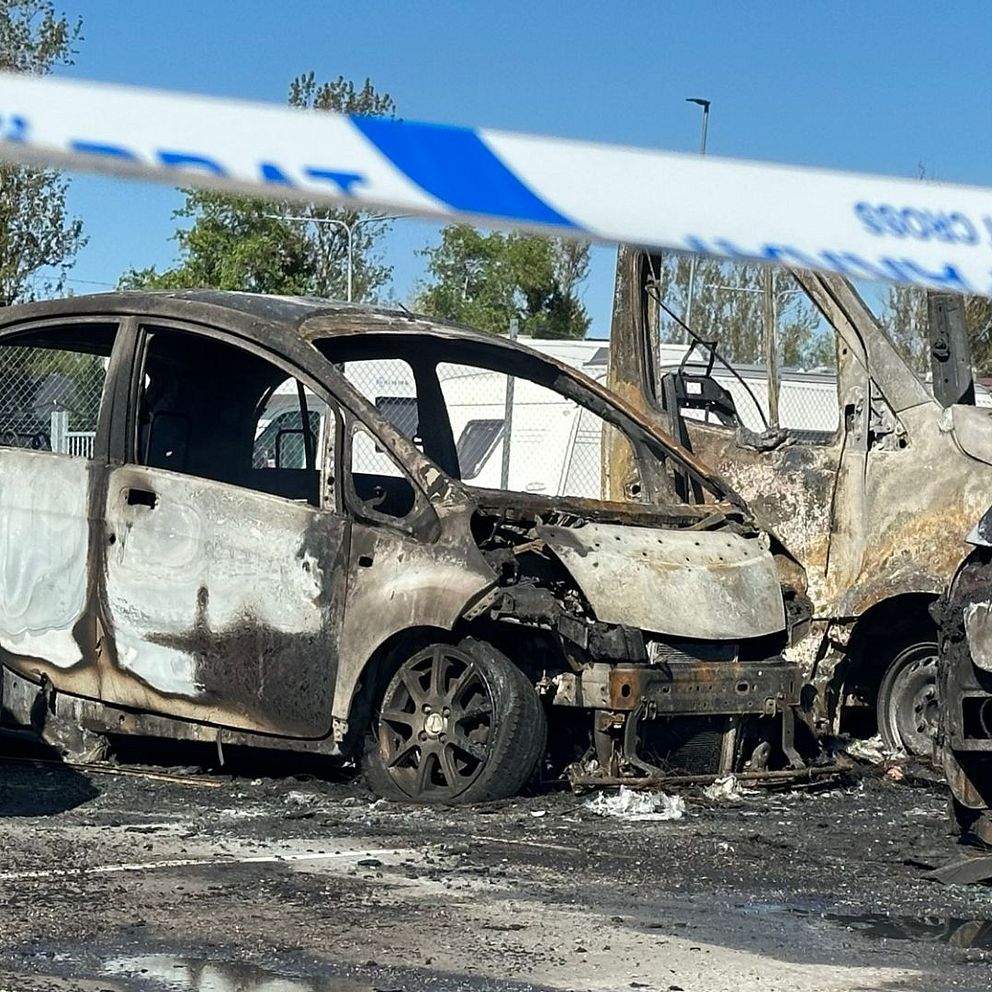 Två utbrunna bilar står på en parkering.