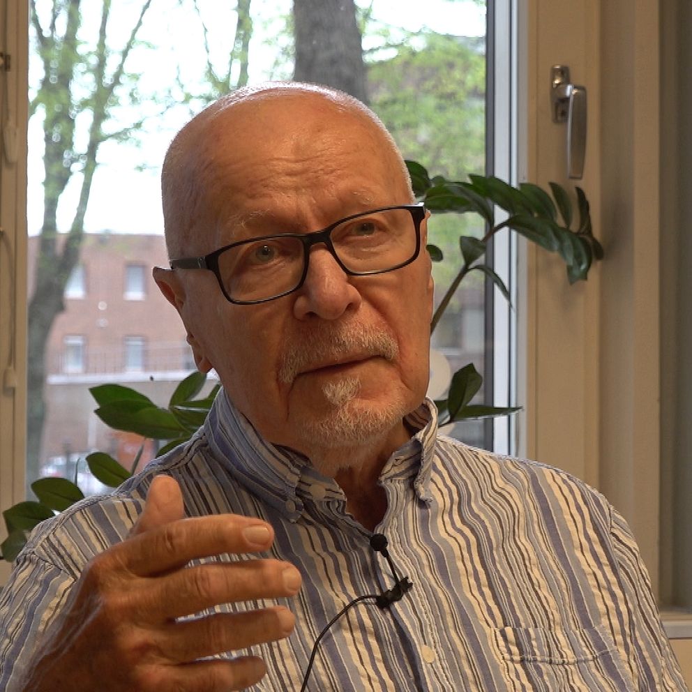 Person i randig skjorta sitter vid fönster och talar