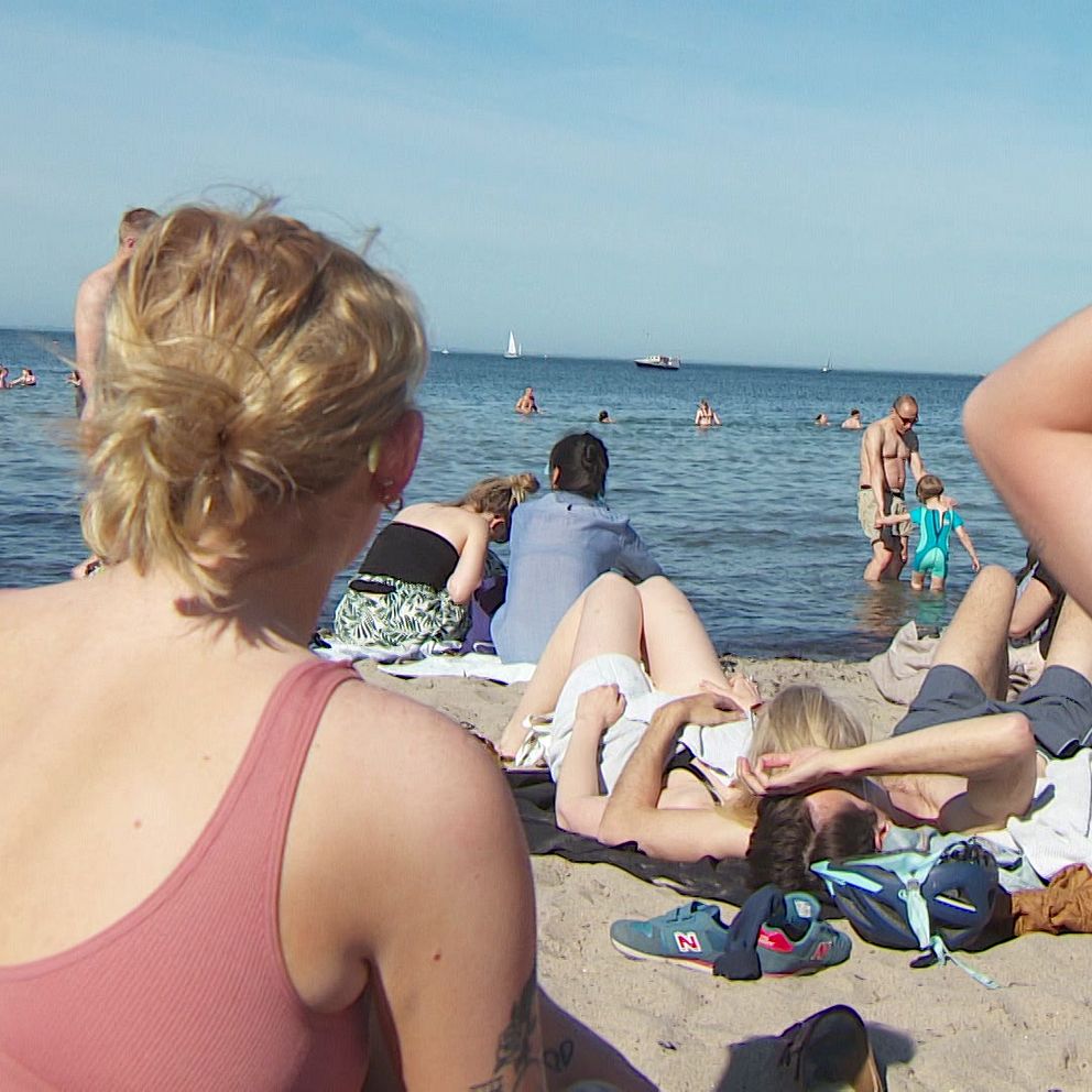 människor som solar och badar på en strand i skåne