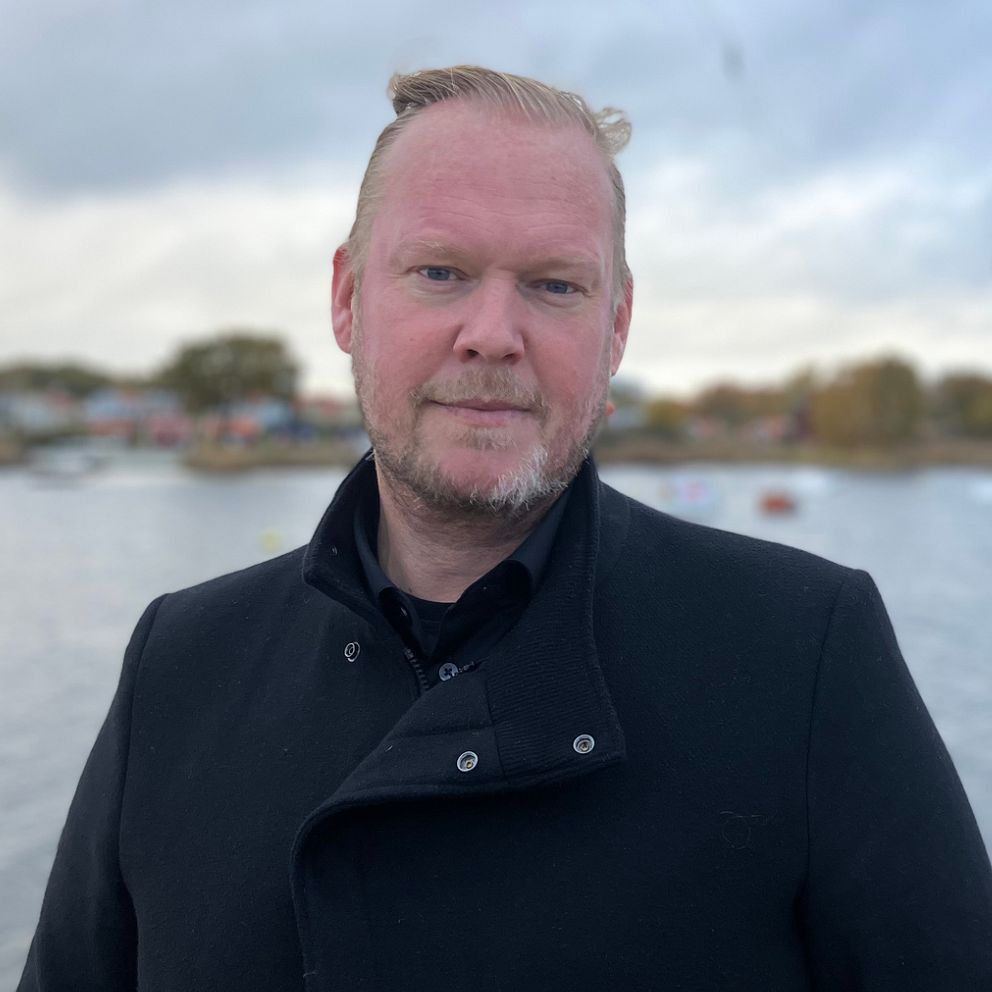 Henrik Nilsson Ederam, förvaltningschef på kultur- och fritidsförvaltningen i Kalmar kommun, står vid vattnet. I bakgrunden skymtar en wakeboardbana och lite hus. Höstfärger syns i omgivningen.