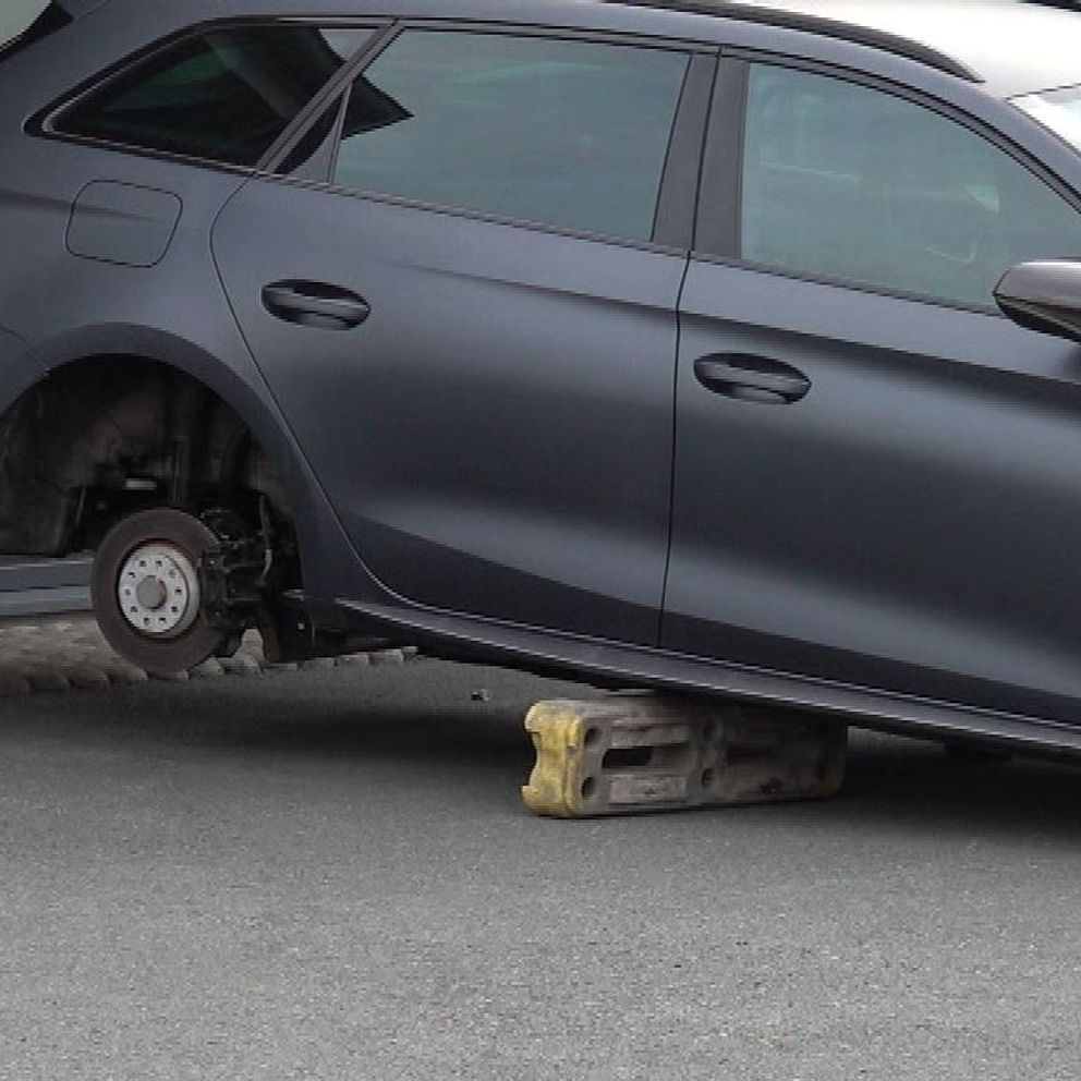 Bil utan hjul står parkerad, uppallad på en domkraft.