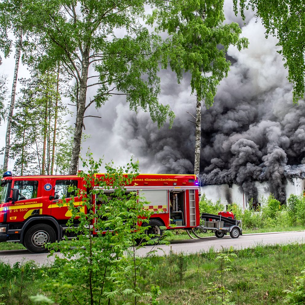 räddningstjänstens bil står framför ett stort moln av mörkgrå rök