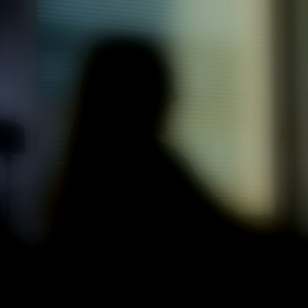 Osäker silhuett i mörker mot oskarp bakgrund.