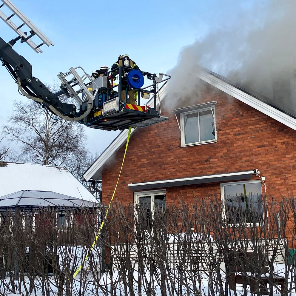Räddningstjänstpersonal i Luleå släcker en brand från en skylift samtidigt som det ryker kraftigt från villataket.