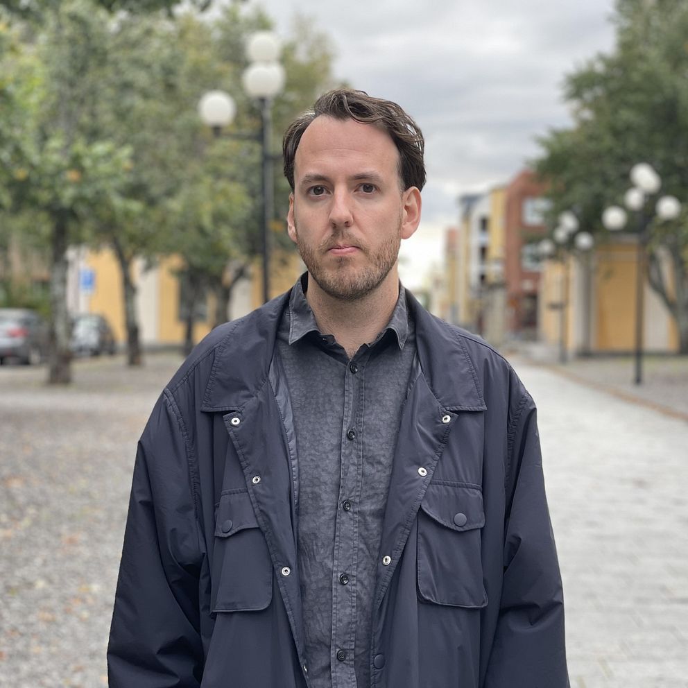 En man med blå skjorta med sammanbiten min.