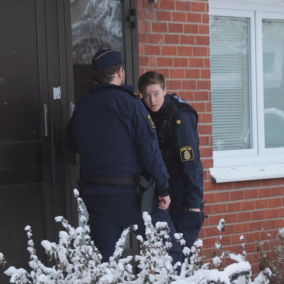 Poliser framför en dörr.