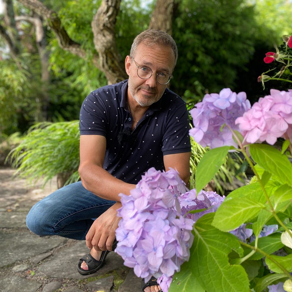 Trädgårdsodlare Per Härdin bakom blommor i sin trädgård