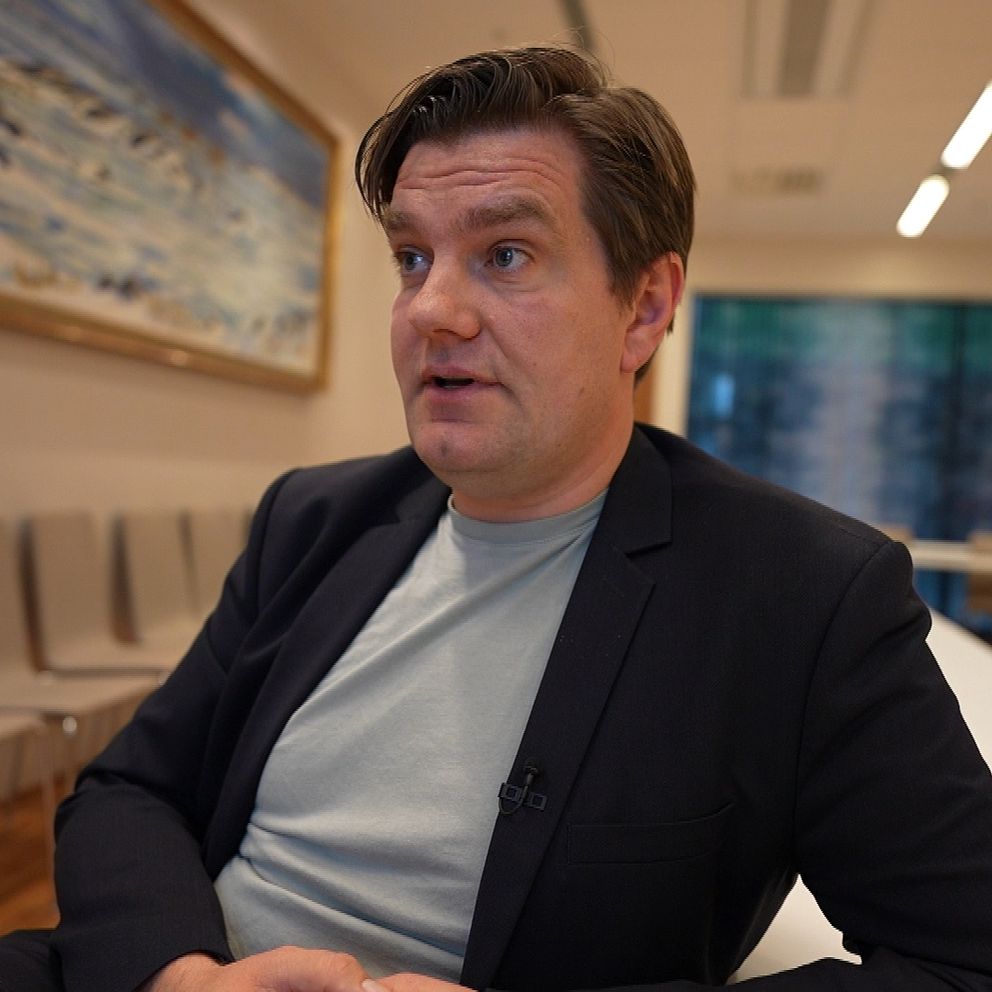 en man i svart kavaj och grå t-shirt