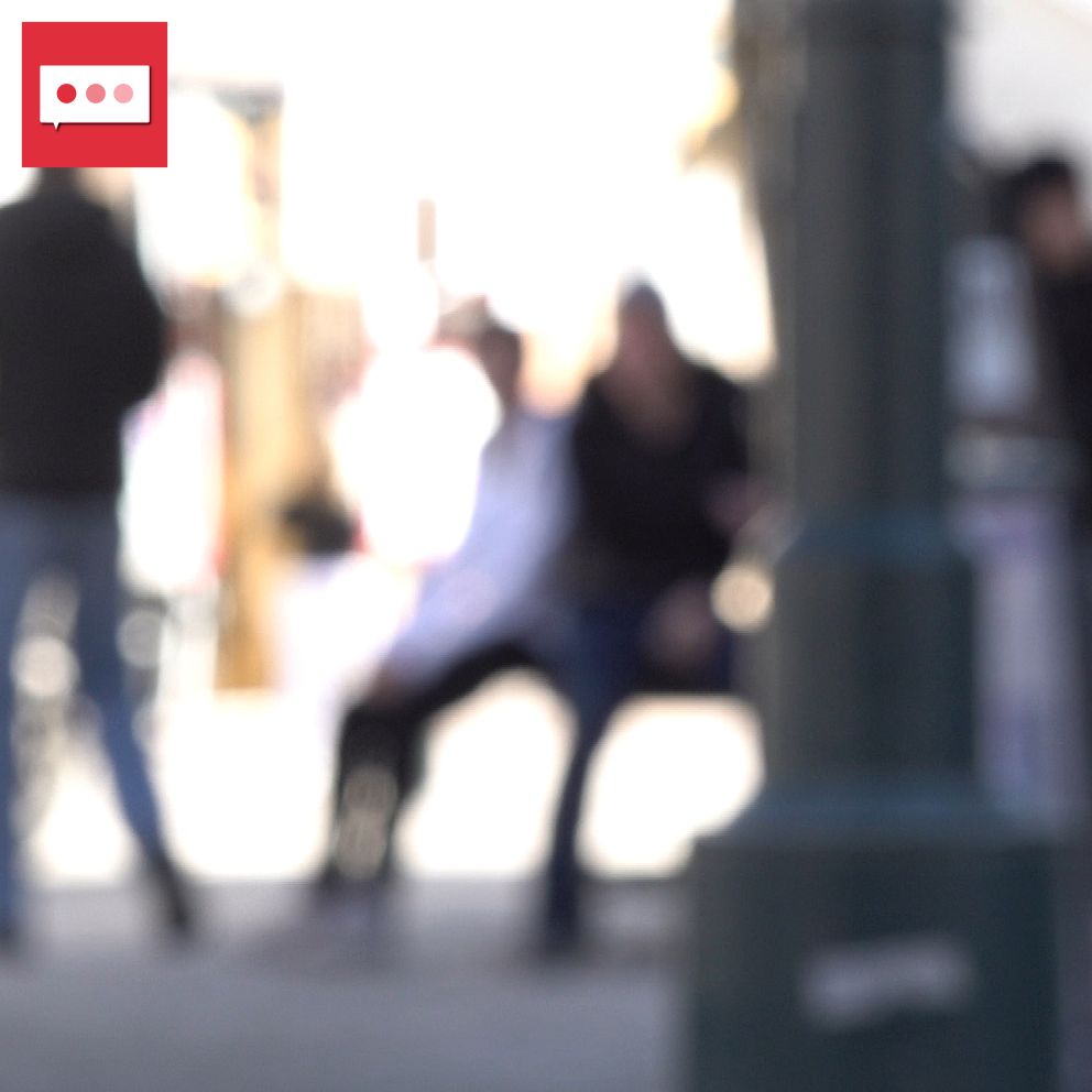 Otydlig bild av människor som sitter och står på en stadsgata.