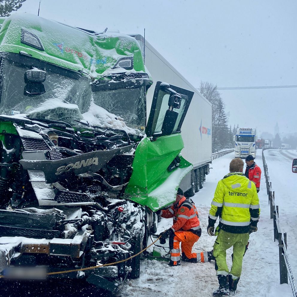 skadad front på en lastbil och räddningspersonal som arbetar efter en snötäckt väg